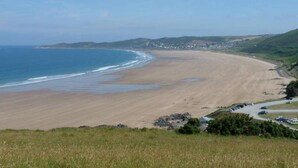 Eine Küstenlandschaft mit Sandstrand, einer kleinen Siedlung und einer Straße, die zum Strand führt.