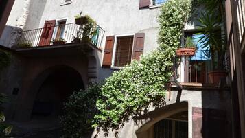 Un edificio rustico con un arco in pietra, balconi in legno e piante in vaso.