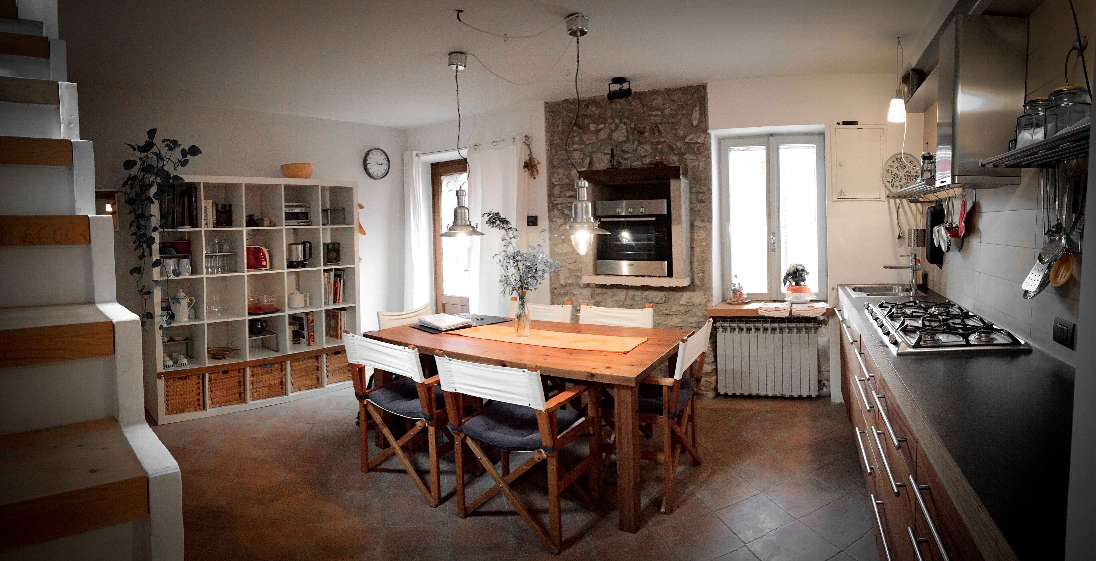 A kitchen with a wooden table, chairs, a built-in oven, and a stove.