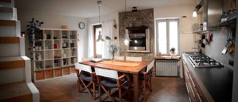 A kitchen with a wooden table, chairs, a built-in oven, and a stove.