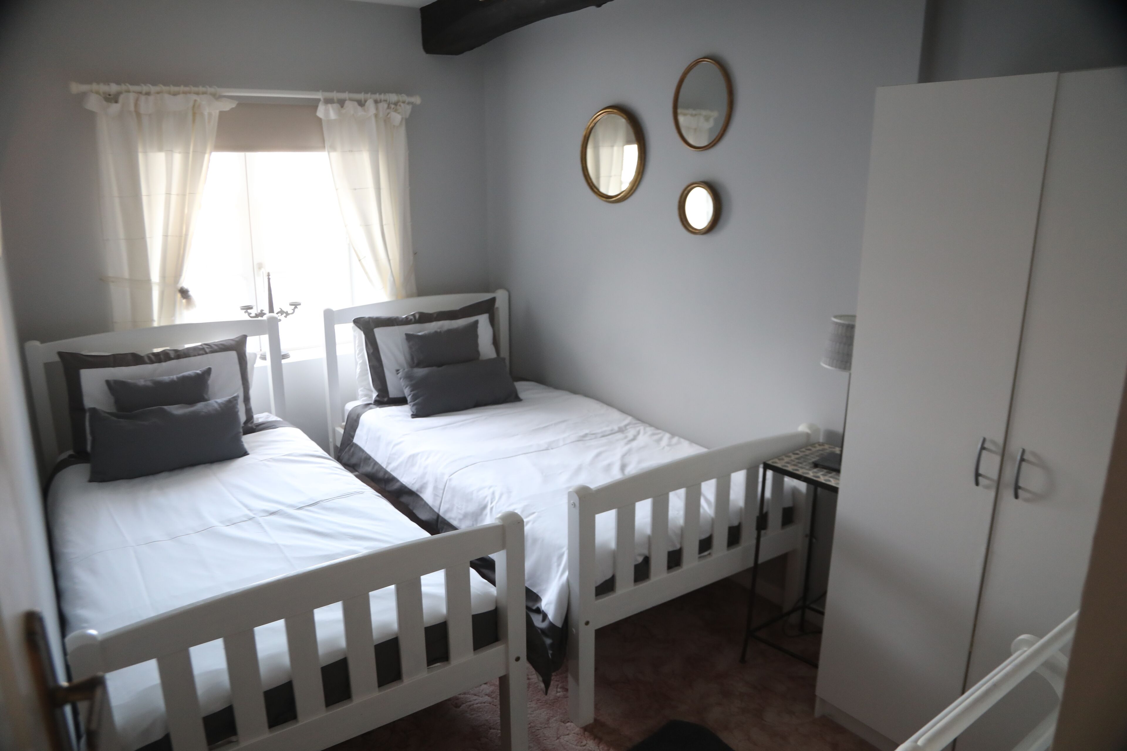 Une chambre avec deux lits simples, une petite table et une armoire.