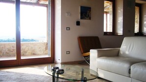 A living room with a glass coffee table, a white sofa, a patterned rug, and a view through large windows. - Private Villa with Infinity Pool - Fantastic Views and Sunsets. (Montecchio, Terni)