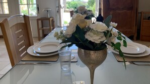 A dining table with white plates, a glass, and a vase with white flowers. - Gite au Manoir de Carlucet, 13th Century, between Sarlat and Montignac, Dordogne (Saint-Crepin-et-Carlucet)