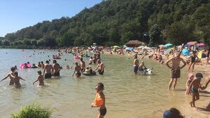 A crowded beach with people swimming and playing in the water, surrounded by lush green hills. - Gite au Manoir de Carlucet, 13th Century, between Sarlat and Montignac, Dordogne (Saint-Crepin-et-Carlucet)