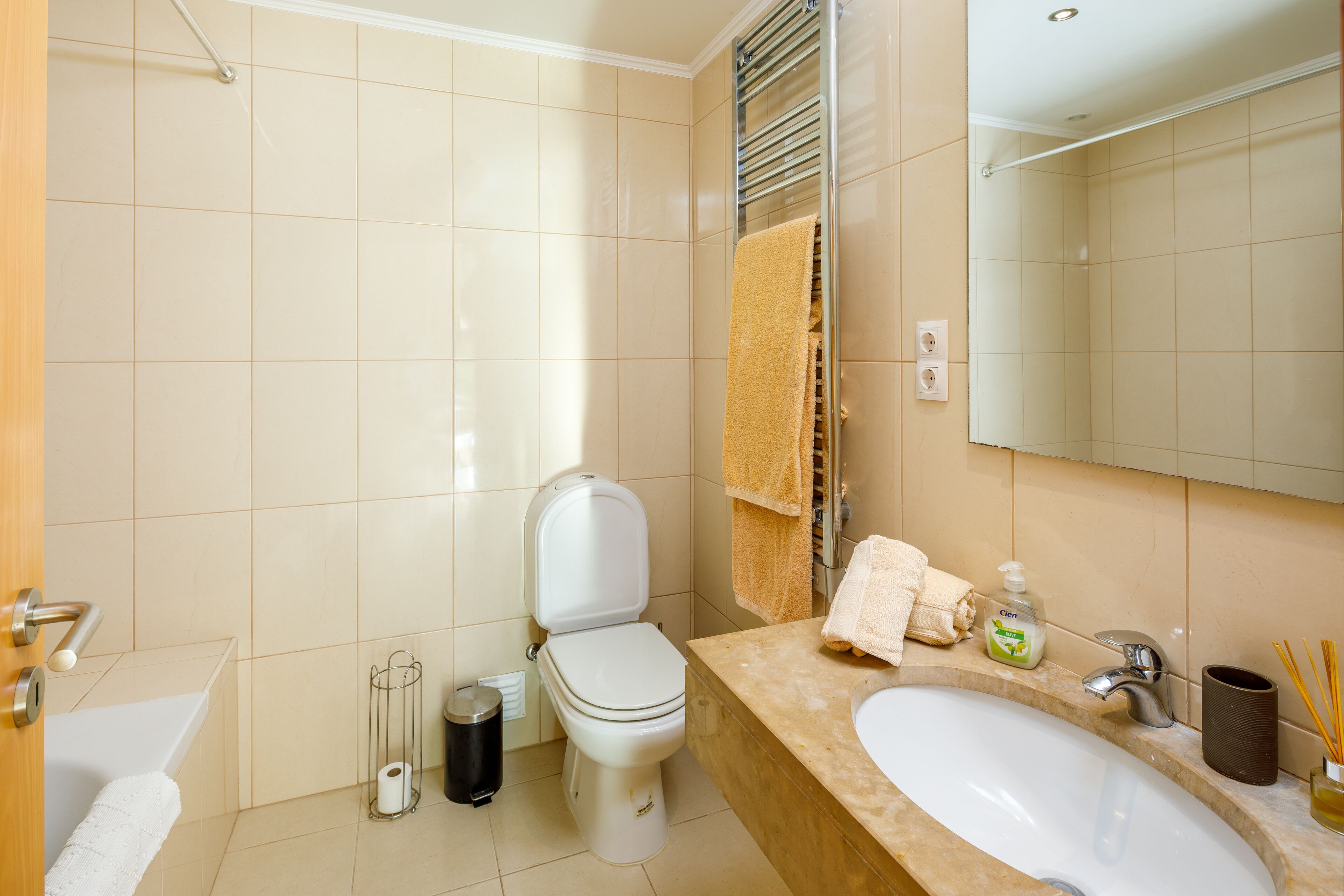 Een badkamer met toilet, wastafel, spiegel en handdoekhouder.