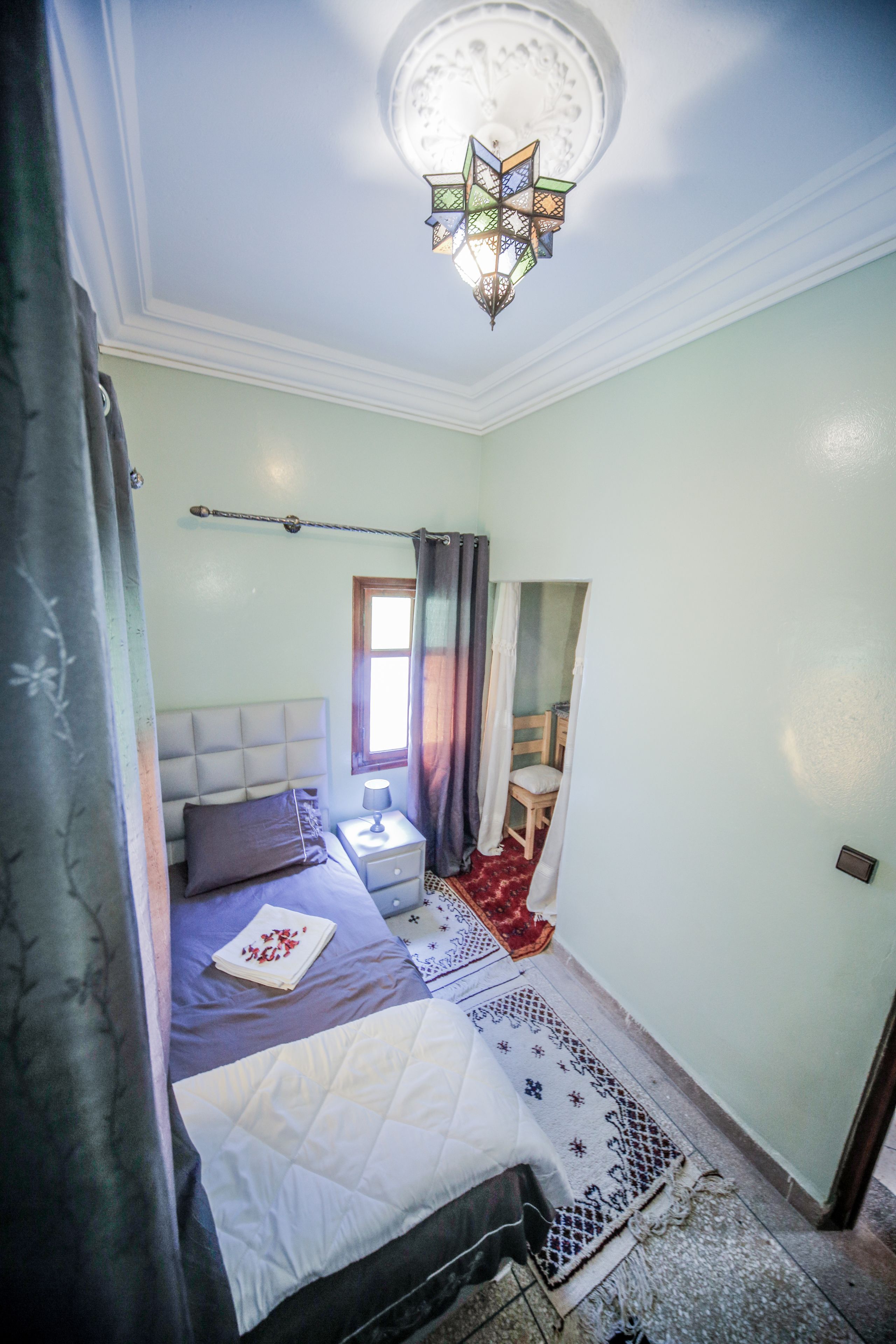 A bedroom with a bed, bedside table, lamp, and a decorative ceiling light.
