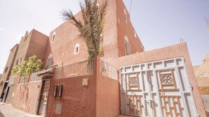A traditional building with a flat facade, a palm tree, and a gated entrance. - Dar Widad - Hostel (Tarmigt)