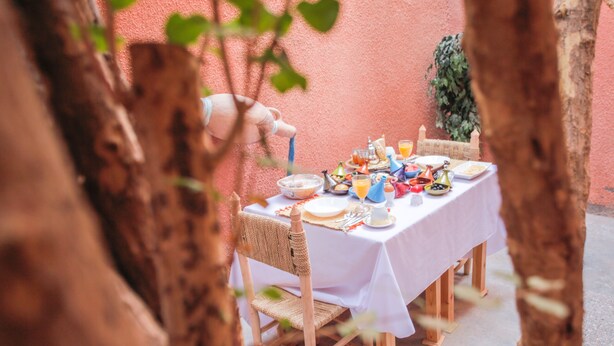 A table set for breakfast with various dishes and drinks, surrounded by trees. - Dar Widad - Hostel (Tarmigt)