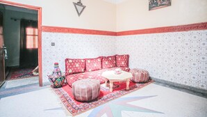 A cozy room with a patterned sofa, ottomans, a small table, and a decorative bowl. - Dar Widad - Hostel (Tarmigt)