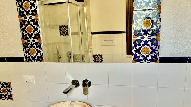 Une salle de bain avec un lavabo, une douche et un miroir.