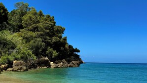 Un paysage côtier caractérisé par une eau turquoise et limpide, un rivage rocheux et une végétation luxuriante.