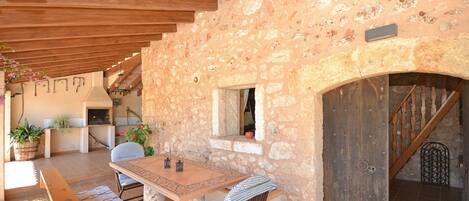 A rustic stone interior with a wooden table, benches, and a small window.