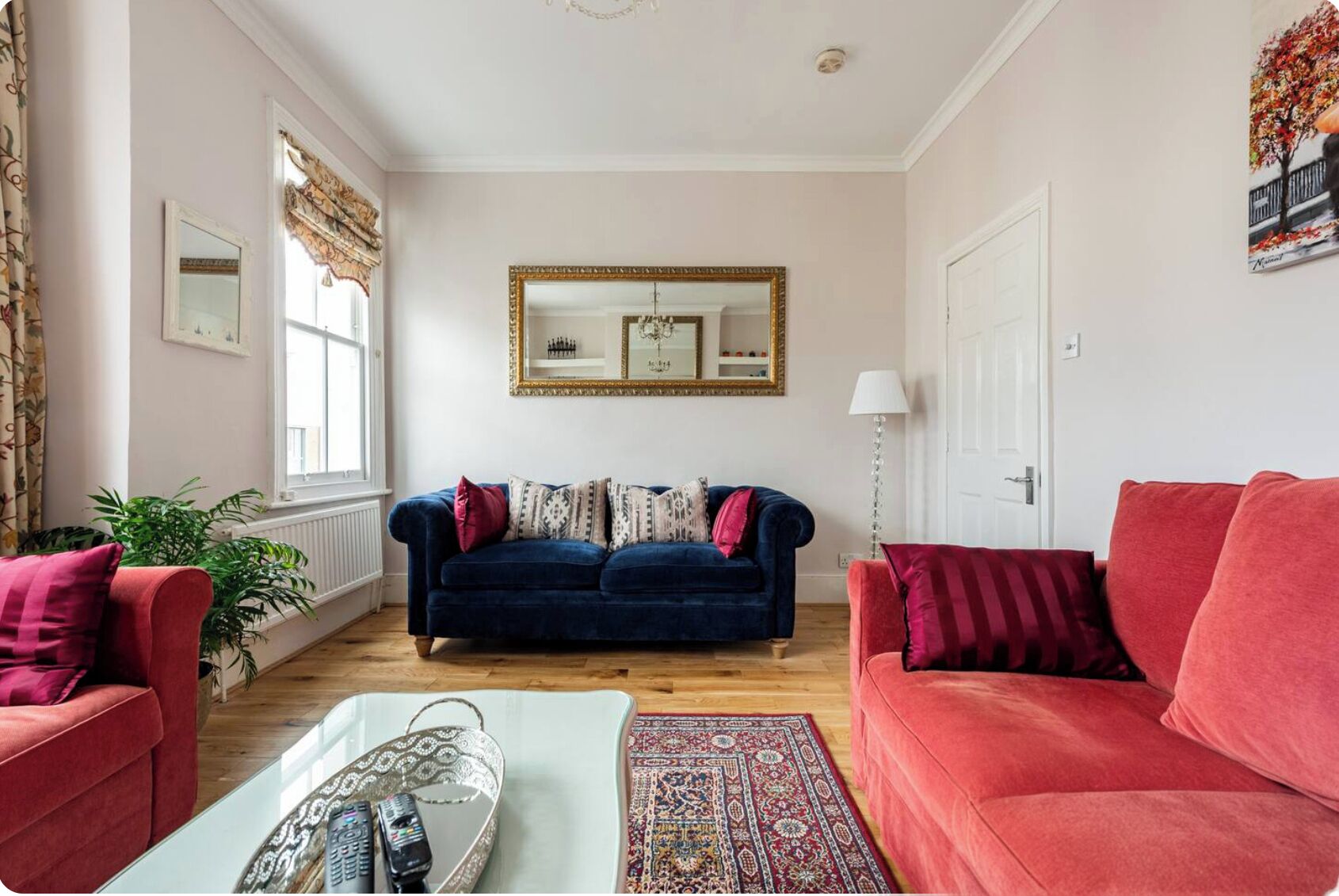 A living room with a blue sofa, red armchairs, a coffee table, and a patterned rug.