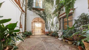 A courtyard with a tiled floor, potted plants, and a central gate. - San José 3 by Home at Homes (Sevilla)