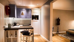 A compact kitchen with white cabinets, a black countertop, and a wooden floor. - Quiboo (Brasov)