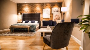 A modern bedroom with a brick wall, a bed with a patterned bedspread, a grey armchair, and a small table. - Quiboo (Brasov)