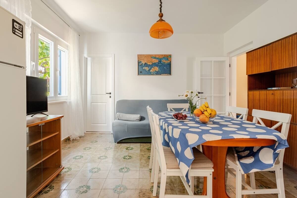 A compact living space with a dining table, chairs, a sofa, a television, and a wooden cabinet.