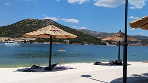 Una playa con sombrillas, un bote y una montaña al fondo.