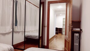 Une chambre à coucher avec un lit, une porte en bois, un radiateur et un petit bureau avec un ordinateur.