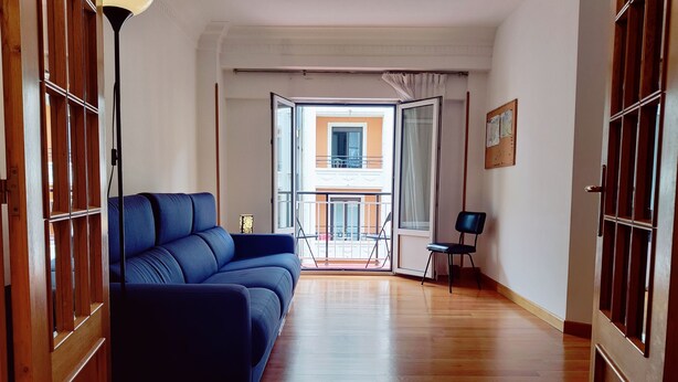 Un salon moderne avec un canapé bleu, un plancher en bois et une vue sur un balcon.