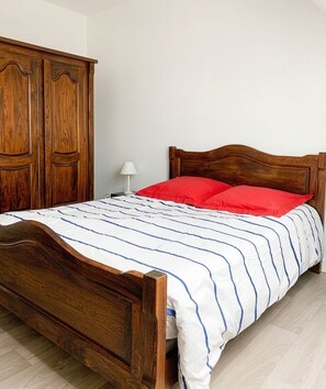 A wooden bed with a striped bedspread and two red pillows.