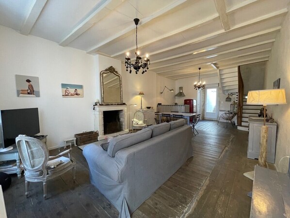 A spacious living room with a fireplace, a sofa, a television, and a chandelier.