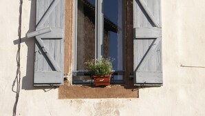 Una ventana con contraventanas de madera y una planta en maceta.