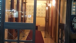 A hotel entrance with a glass door, a red carpet, and a hallway leading inside.