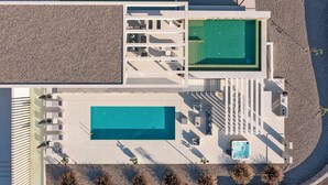 An aerial view of a modern hotel with two swimming pools, outdoor seating areas, and a hot tub. - Amara Luxury villas (Rhodes)
