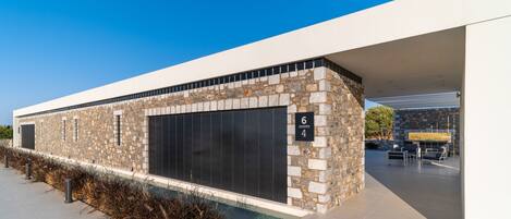 A modern building with a stone facade, large windows, and a covered outdoor seating area.