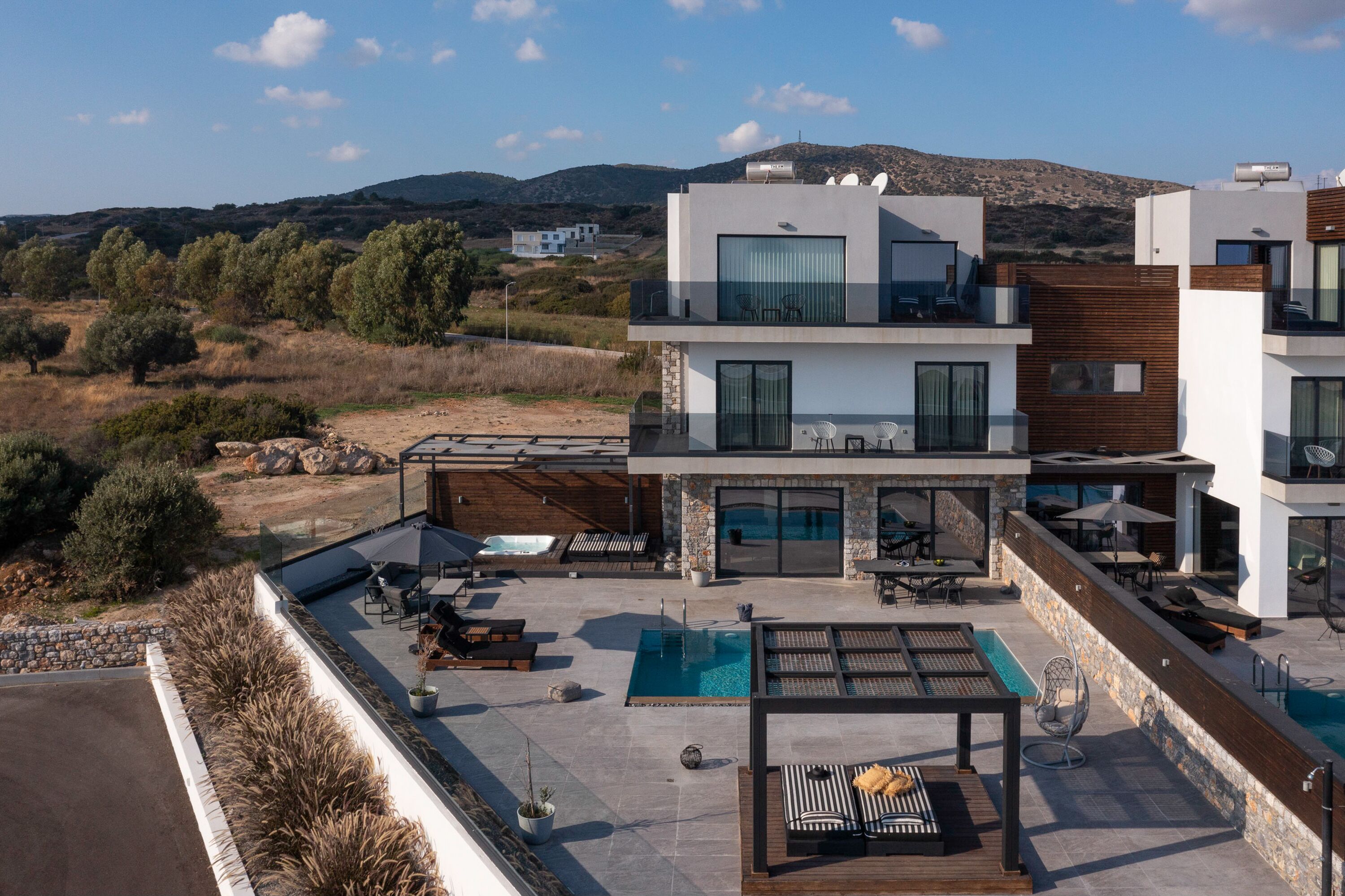 Un edificio moderno a più piani con piscina sul tetto, area salotto esterna e vista sul paesaggio circostante.
