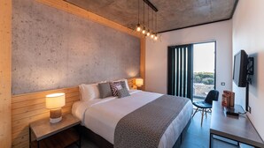 A modern bedroom with a large bed, bedside tables, a desk, and a TV. - Amara Luxury villas (Rhodes)