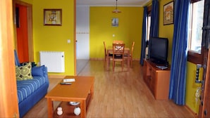 Een woonkamer met een bank, een tafel, een televisie en een eethoek.
