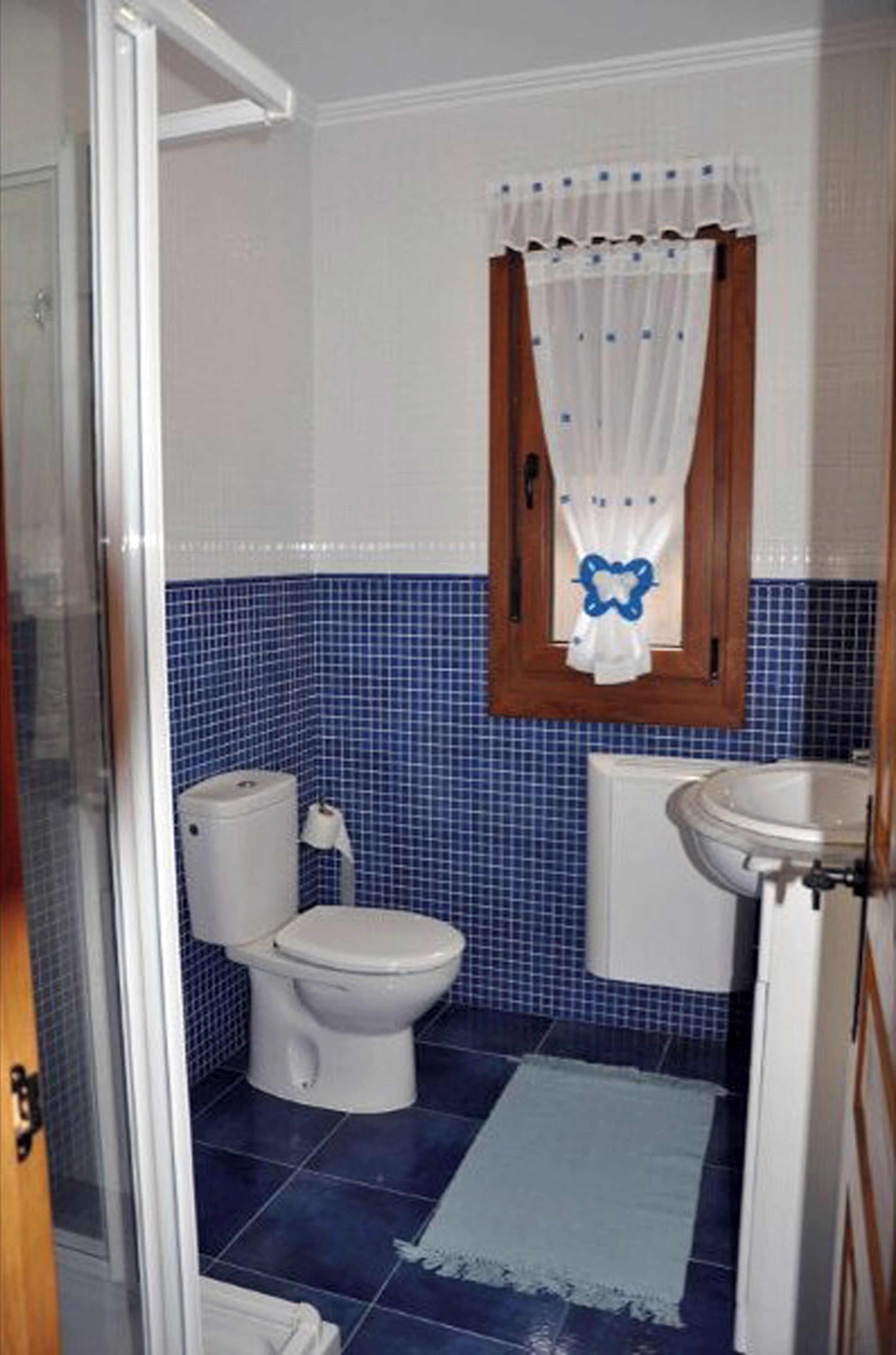 Ein Badezimmer mit Toilette, Waschbecken und blauen Fliesen.