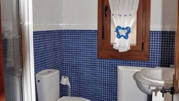 Ein Badezimmer mit Toilette, Waschbecken und blauen Fliesen.