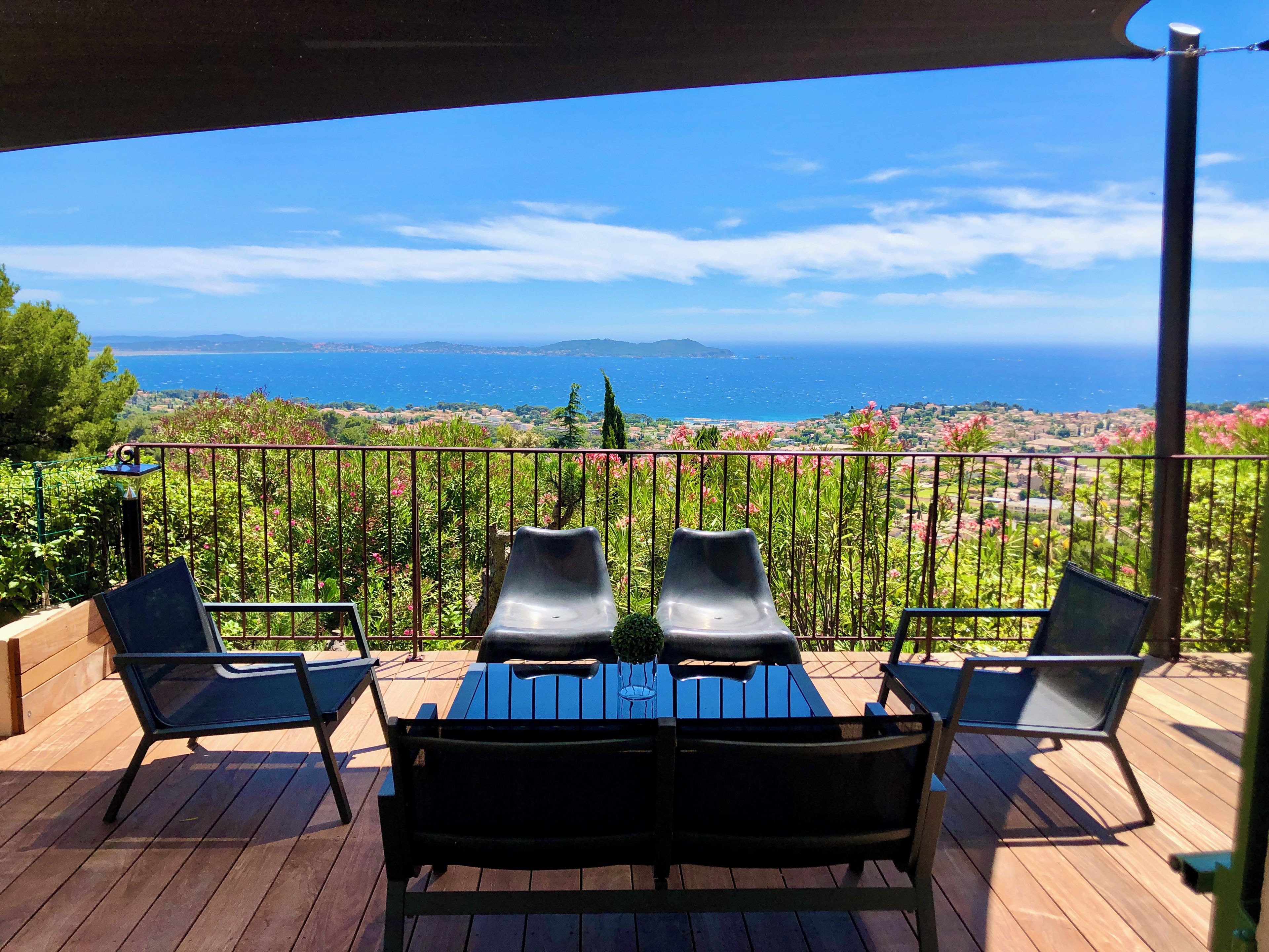 Une terrasse avec une table et des chaises, offrant une vue panoramique sur la mer et le paysage.