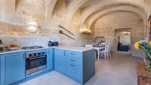 Una cocina con armarios azules, horno integrado y un arco de piedra.