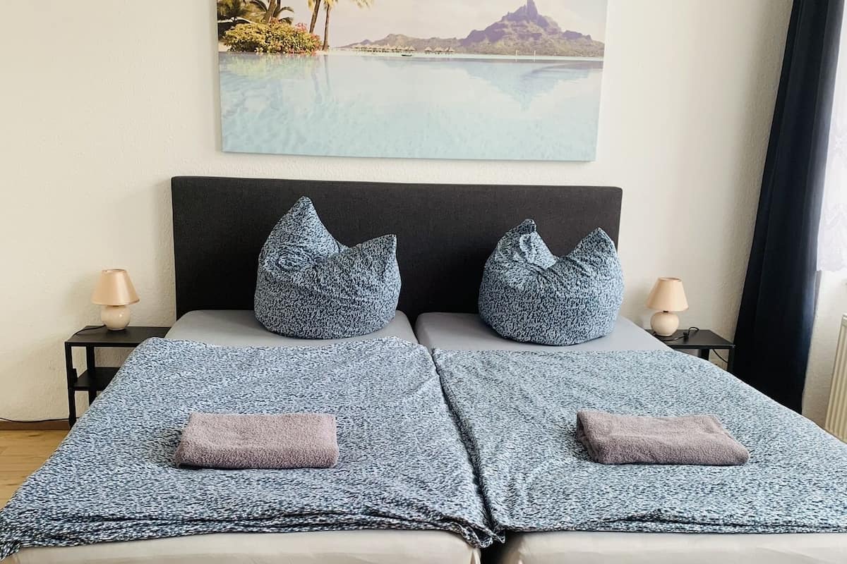 A double bed with a grey and white patterned bedspread, two matching pillows, and a pair of bedside lamps.