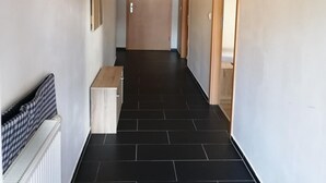 A hallway with a wooden ceiling, black tiled floor, and a bench on the left. - Pension Kellei 71 (Dresden)