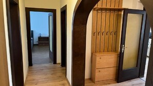 A hallway with wooden flooring, a dark wooden door with a glass panel, and a wooden cabinet with hooks. - Pension Kellei 71 (Dresden)