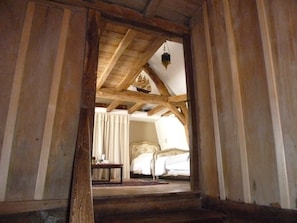 Eine Holztreppe führt zu einem Schlafzimmer mit einem Bett und einer Pendelleuchte.