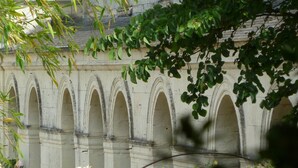 Um edifício de pedra com várias arcos e um jardim com plantas floridas.