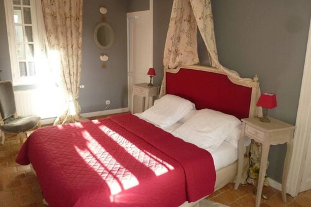 A bedroom with a bed, two bedside tables, a chair, and a window with curtains.