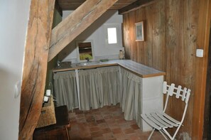 A small kitchen with a wooden ceiling, a sink, a window, and a chair. - Le Manoir de Boisairault (Le Coudray-Macouard)