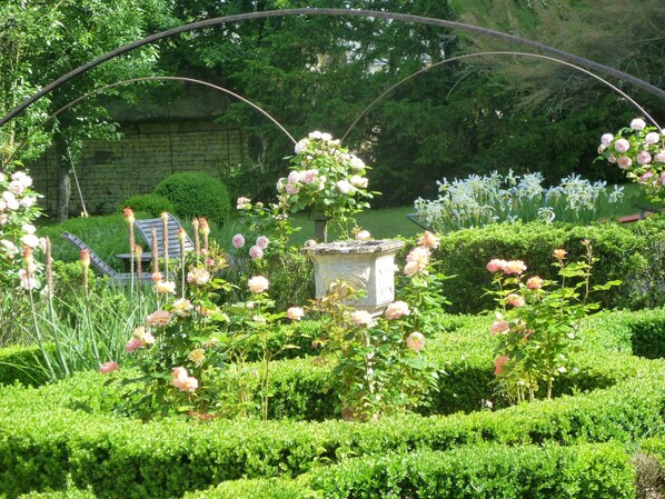 A garden with neatly trimmed hedges, a stone fountain, and blooming pink roses. - Le Manoir de Boisairault (Le Coudray-Macouard)