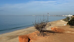 A coastal landscape with a sandy beach, a small shrub, and a distant cityscape. - Villa Flores, Vale do Lobo - modern 4 bed, 4 bath, south facing villa with pool  (Almancil)