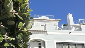 A white building with a tiled roof, a gated entrance, and a clear blue sky. - Villa Flores, Vale do Lobo - modern 4 bed, 4 bath, south facing villa with pool  (Almancil)