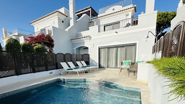 A poolside area with a clear blue pool, white walls, and a covered seating area with lounge chairs. - Villa Flores, Vale do Lobo - modern 4 bed, 4 bath, south facing villa with pool  (Almancil)