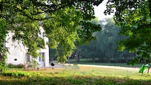 Un espace extérieur avec un bâtiment blanc, une pelouse verdoyante et des arbres.