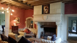 Un salon traditionnel avec une cheminée, des canapés recouverts de tissu blanc et un mur d’accent rouge.